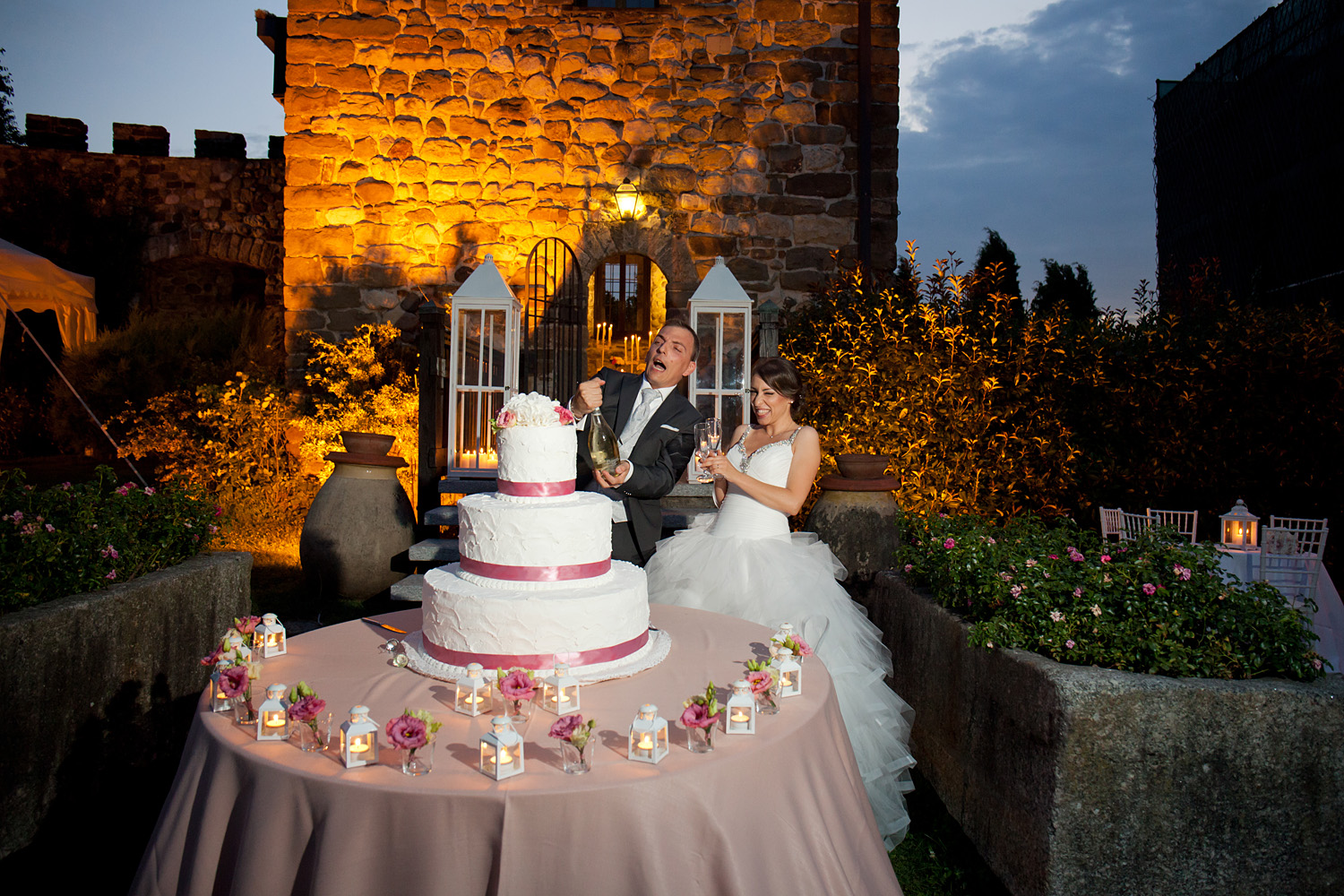 Castello di Rossino Il momento del taglio della torta nuziale con lo Sposo che sta stappando la bottiglia di spumante